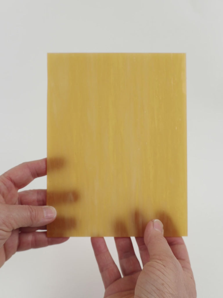 Video of the honey blonde glass plate in beige translucent, 15x19cm, held up and tilted to show its pattern and transparency