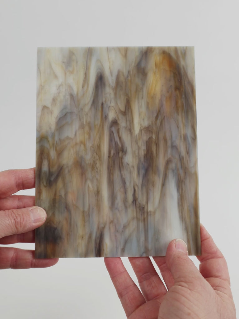 Video of the limestone glass plate in beige, 15x19cm, held up and tilted to show its pattern and transparency
