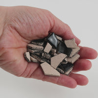 Video of Flip ceramic puzzle pieces in black, opaque glazed porcelain, 4–20 mm, held in a hand and poured out to show their shapes and finish